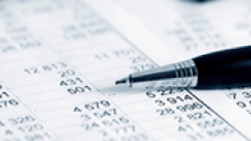 Pen laying on a sheet of paper with finance data printed